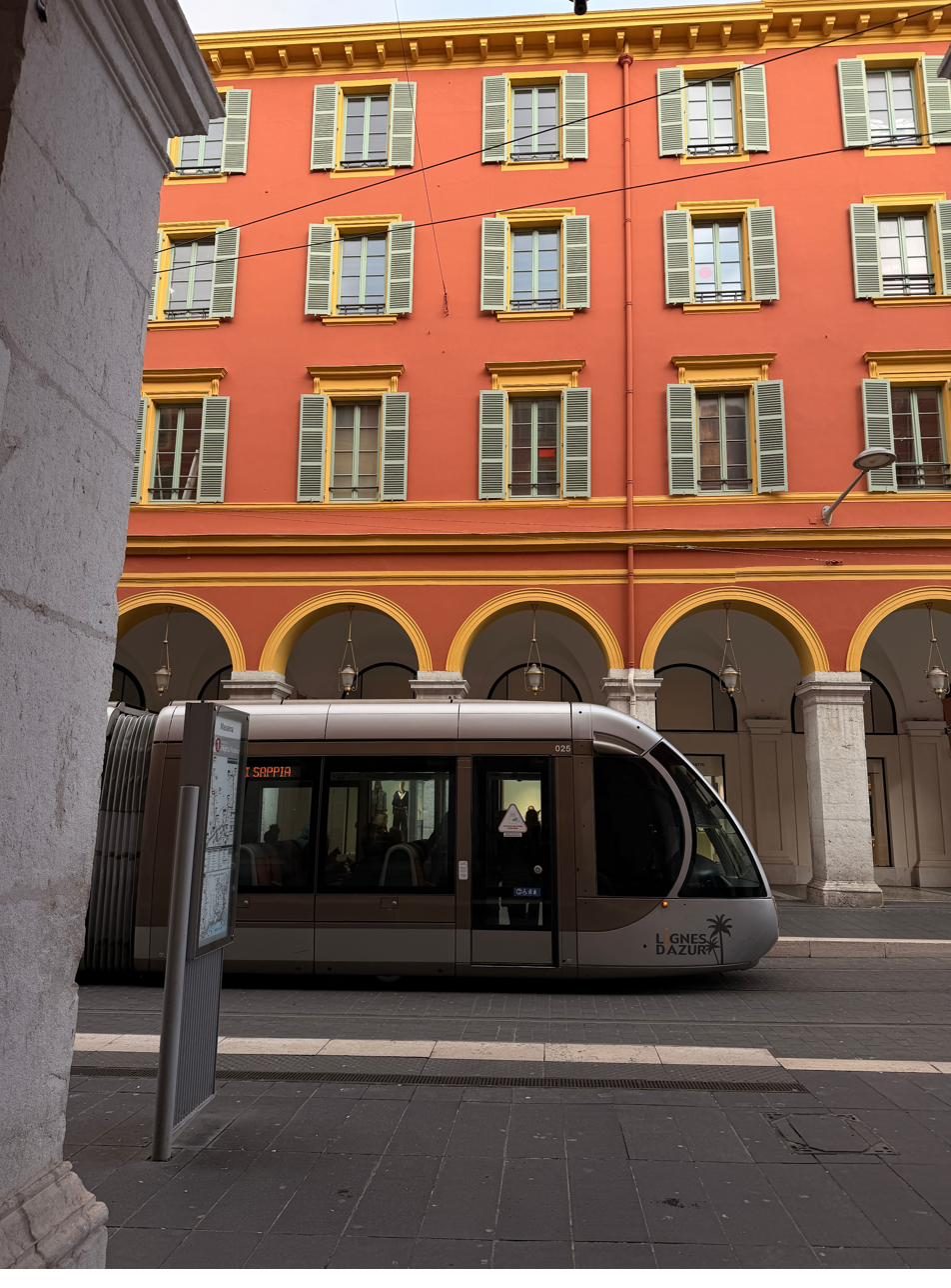 Un tramway de la ligne 1 devant les façades rouges de la place Masséna