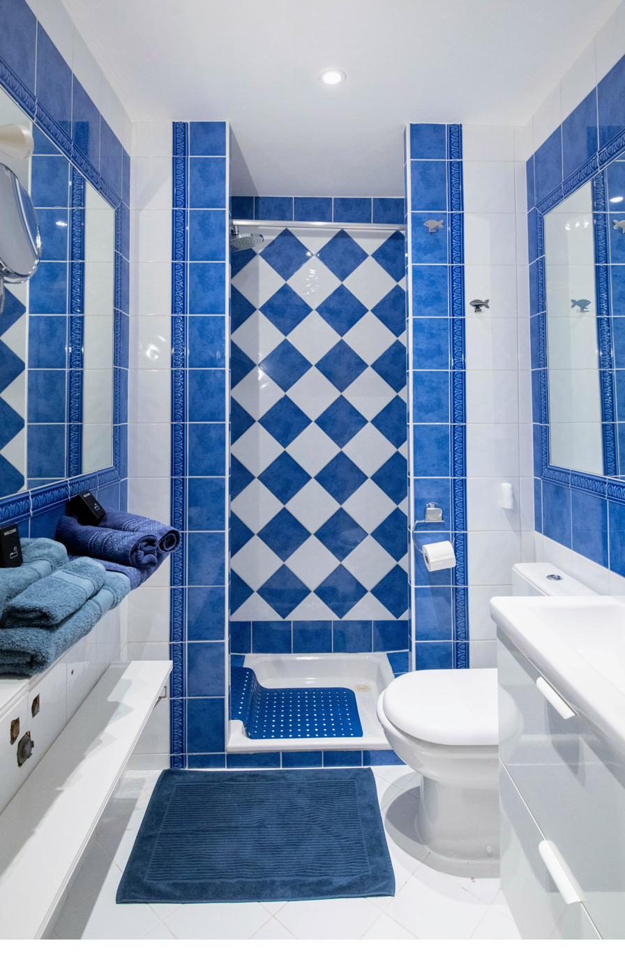 Salle de bain carrelée de bleu avec douche et serviettes
